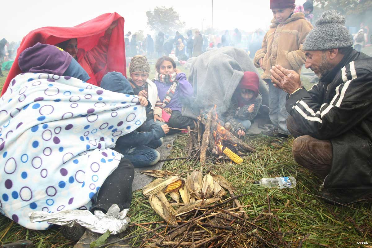 ‪Refugees burn trash to make fire and keep themselves warm at a field near the Slovenian-Croatian border as they wait for the transport to the refugee centre in Brezicein, Slovenia on October 20, 2015