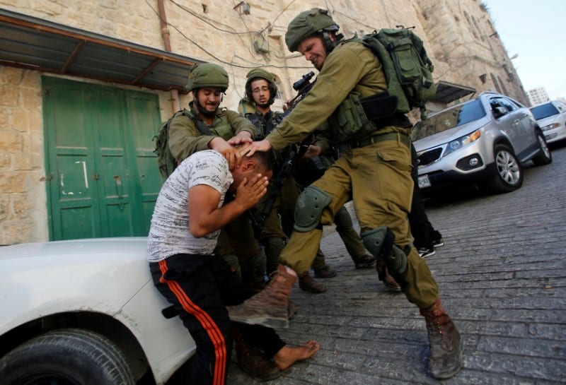 Israeli soldiers detain a Palestinian during a searching raid by Israeli troops, in the West Bank [REUTERS/Mussa Qawasma]
