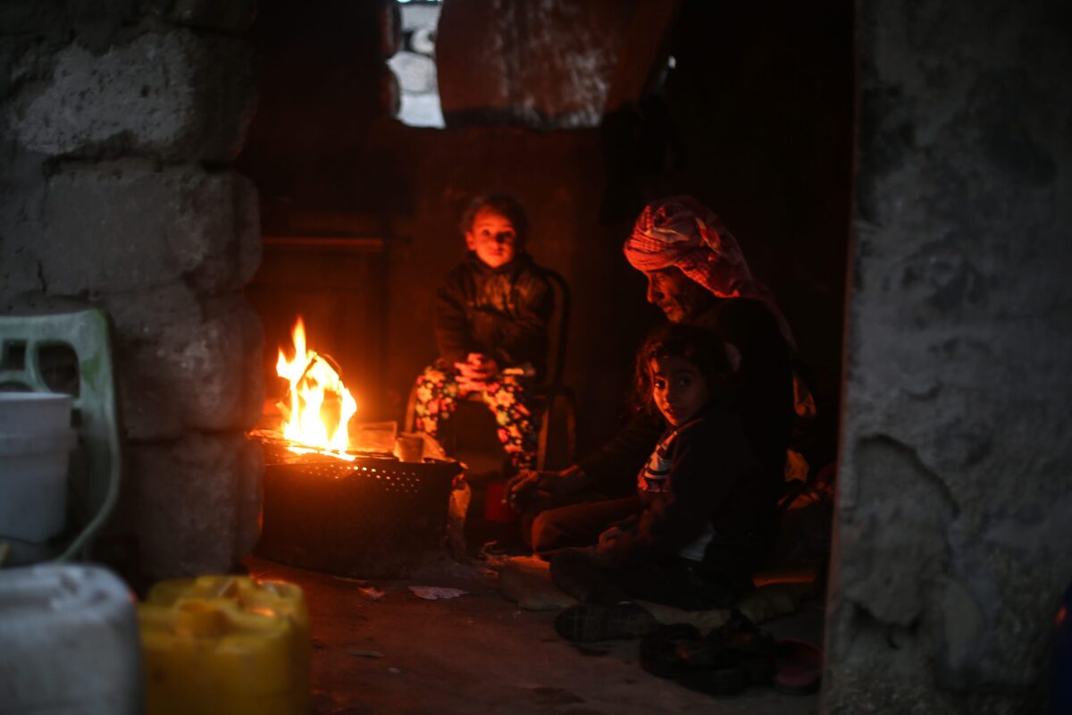 Palestinian children huddle by the fire inside a makeshift home as living conditions deteriorate in Gaza (Mustafa Hassona/Anadolu Agency)