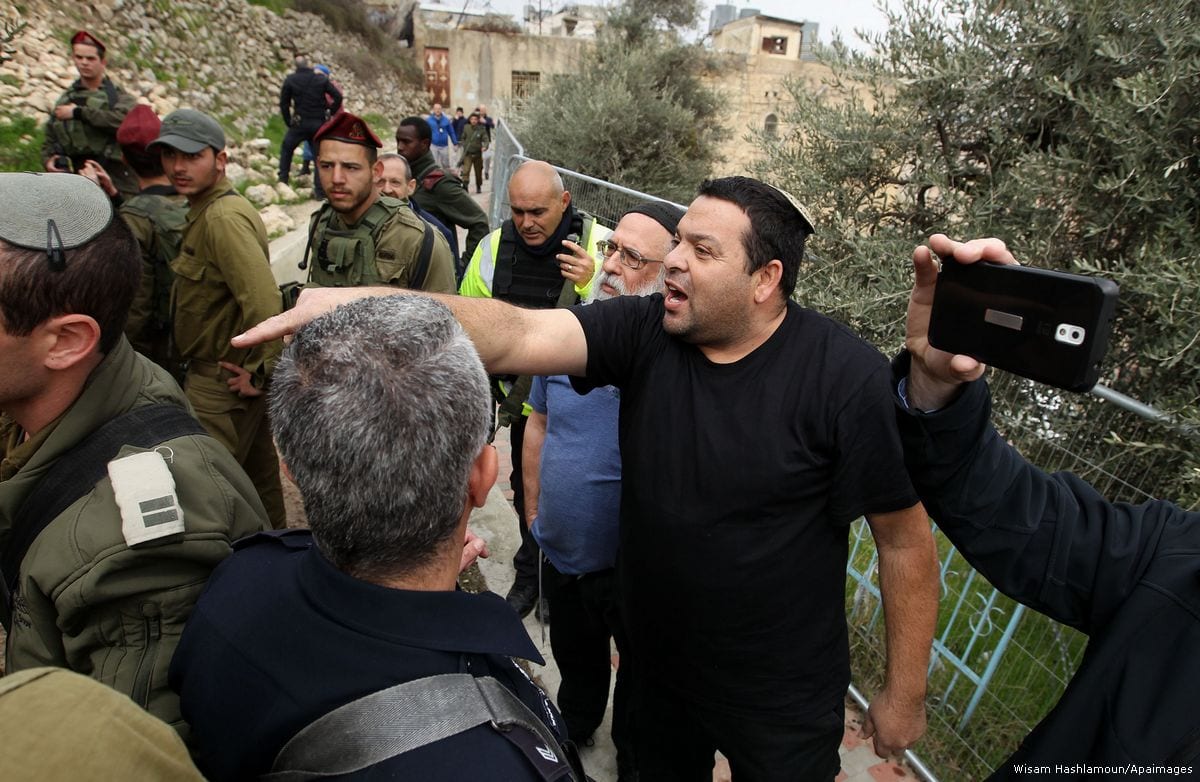 Israeli forces stand in front of Jewish settlers who are harassing Palestinians in the West Bank [Wisam Hashlamoun/Apaimages]