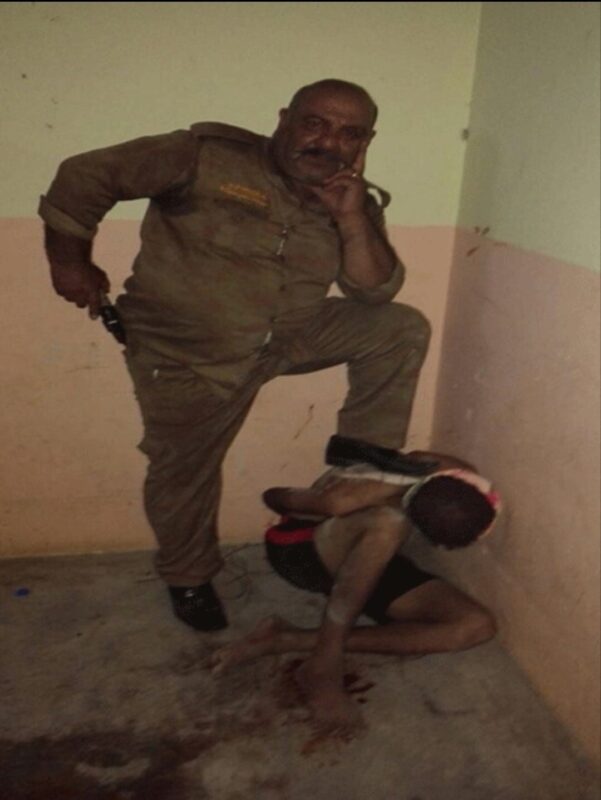Image of an Iraqi Christian militia leader violently stepping on a Iraqi youth