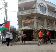 Participants run past the the Walled-Off Hotel, Banksy's newly opened hotel in Bethlehem, West Bank on March 31, 2017. [Wisam Hashlamoun/Apaimages]