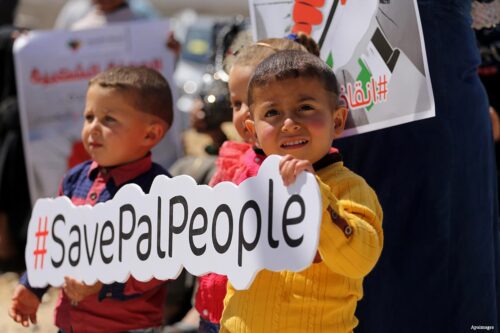 Palestinian activists take part in a rally titled "Save Pal People" against the Israeli occupation and Gaza blockade in front of a tower which was destroyed during the 50-day war between Israel and Hamas in the summer of 2014