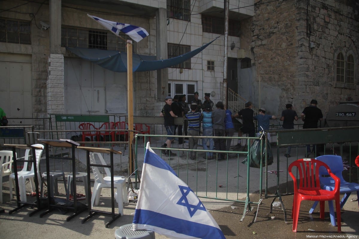 Israeli flags can be seen around a Palestinian house which was illegally occupied by settlers under the protection of occupation forces in the West bank city of Hebron on 26 July 2017. [Mamoun Wazwaz /Anadolu Agency]