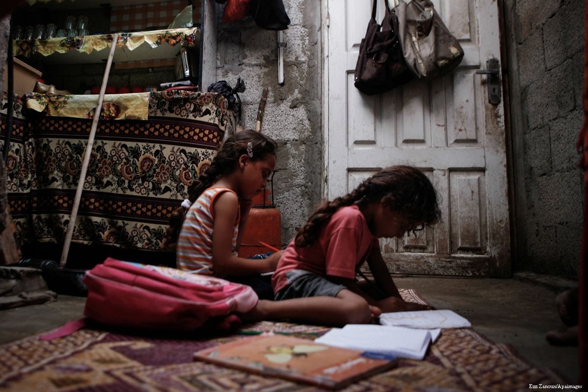 Palestinian children can be seen doing their homework in their makeshift home in one of the poorest neighbourhoods in Gaza [Ezz Zanoun/Apaimages]