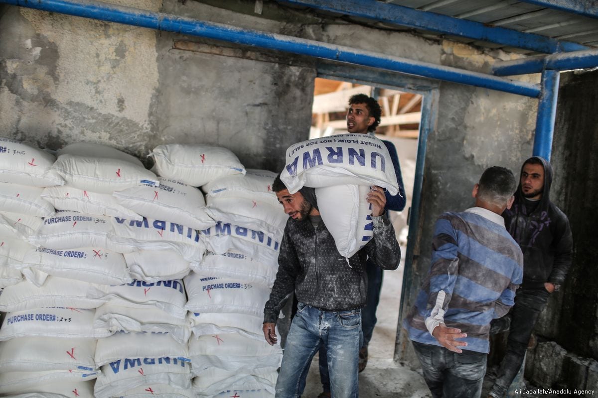 Palestinian men carry food aid given by UNRWA in Gaza City, Gaza on 15 January 2018 [Ali Jadallah/Anadolu Agency]