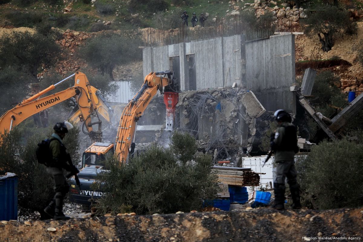 Bulldozers demolish two buildings belongs to Palestinians under the observation of Israeli forces in the West Bank on 29 January 2018 [Mamoun Wazwaz/Anadolu Agency]