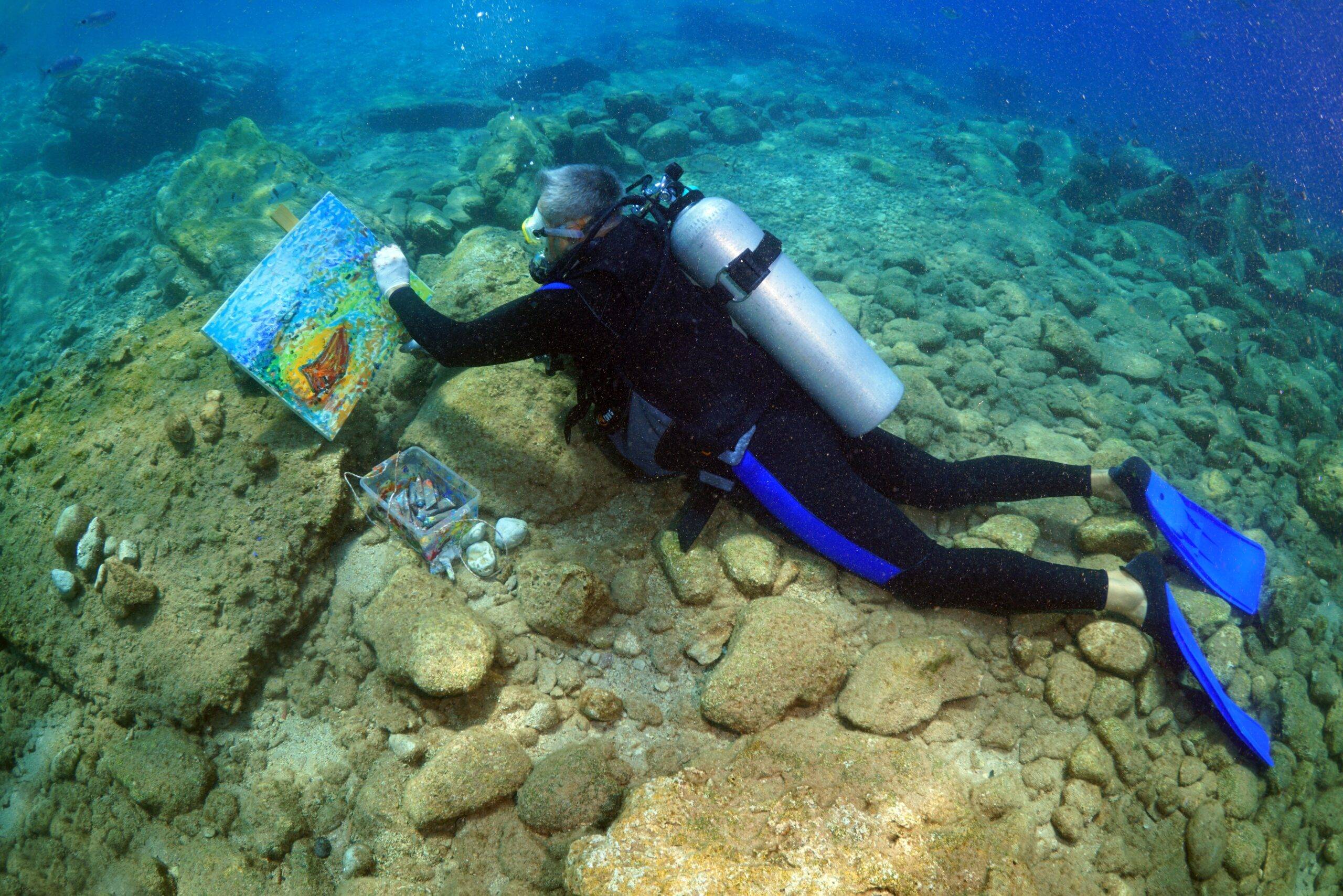 An artist in a wet suit paints a portrait underwater within the "Our International Seas and Colors Underwater Painting Event" in Fethiye district of Mugla, Turkey on 28 April, 2018 [Tahsin Ceylan/Anadolu Agency]