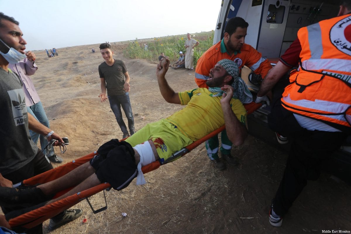 An injured Palestinian is seen taken away as Israeli forces clash with Palestinian protesters at the Gaza and Israel border during the ninth consecutive week of protests, organised as part of the Great March of Return, on 25 May 2018 [Mohammad Asad / Middle East Monitor]