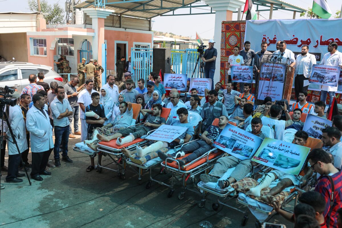First aid crews and patients lying on stretchers take part in a protest against the impairment of health due to Israel's over a decade long blockade in front of Beit Hanoun Border Gate in Gaza City, Gaza on 17 July, 2018 [Mustafa Hassona/Anadolu Agency]