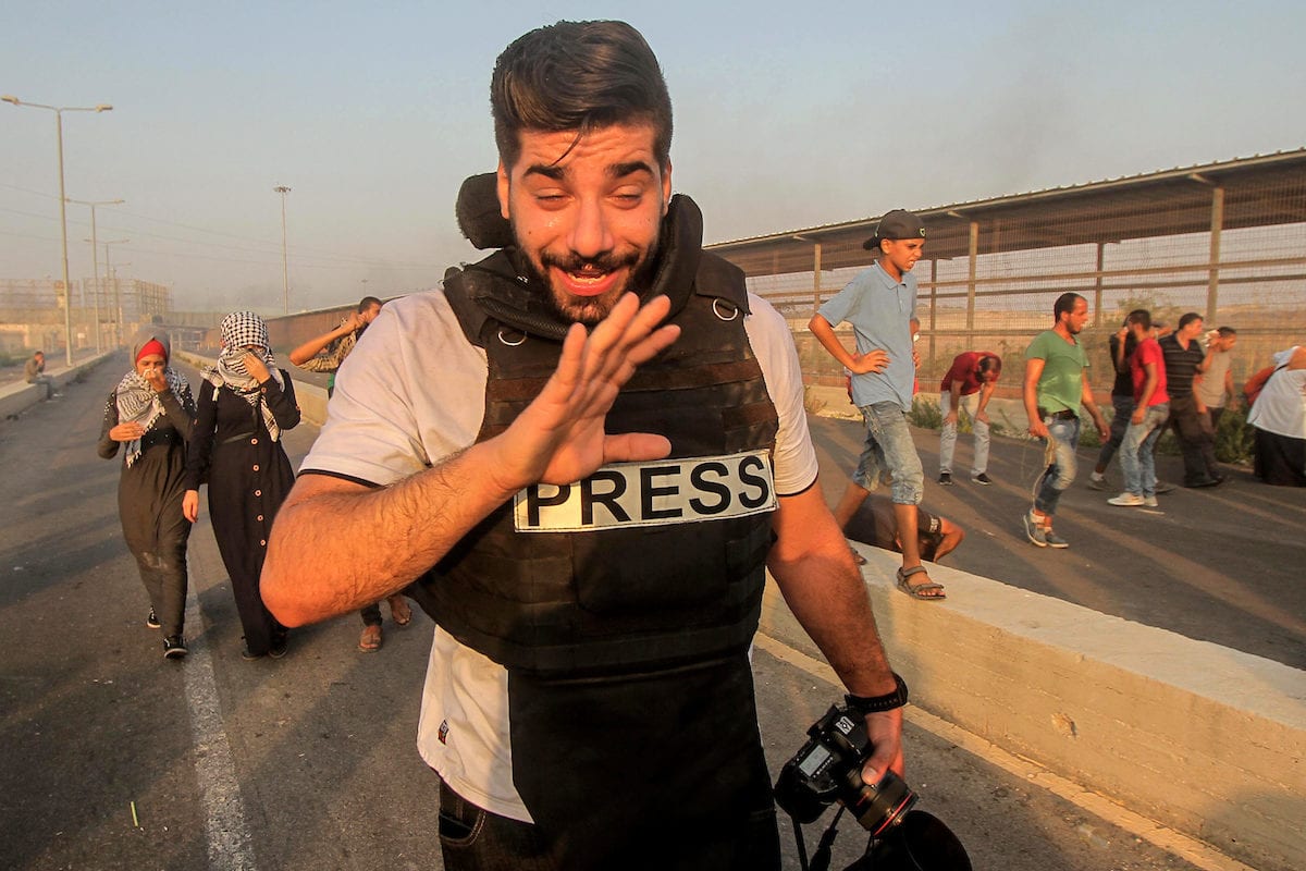 Palestinian journalist and Palestinian protesters gather during clashes with Israeli troops following a protest against the United States decision to stop funding and backing the United Nations agency for Palestinian refugees (UNRWA) at the Erez crossing with Israel in the northern Gaza Strip on 4 September, 2018 [Dawoud Abo Alkas/Apaimages]
