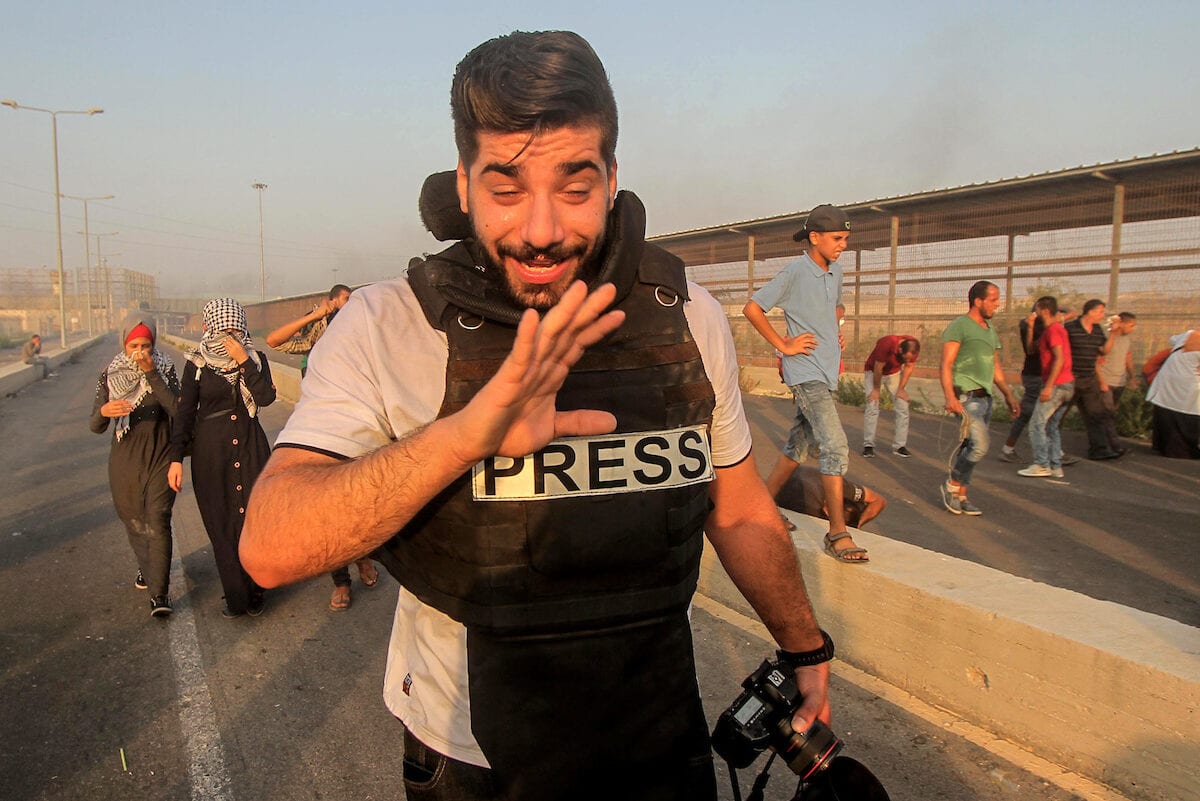 Palestinian journalist and Palestinian protesters gather during clashes with Israeli troops following a protest against the United States decision to stop funding and backing the United Nations agency for Palestinian refugees (UNRWA) at the Erez crossing with Israel in the northern Gaza Strip on 4 September, 2018 [Dawoud Abo Alkas/Apaimages]