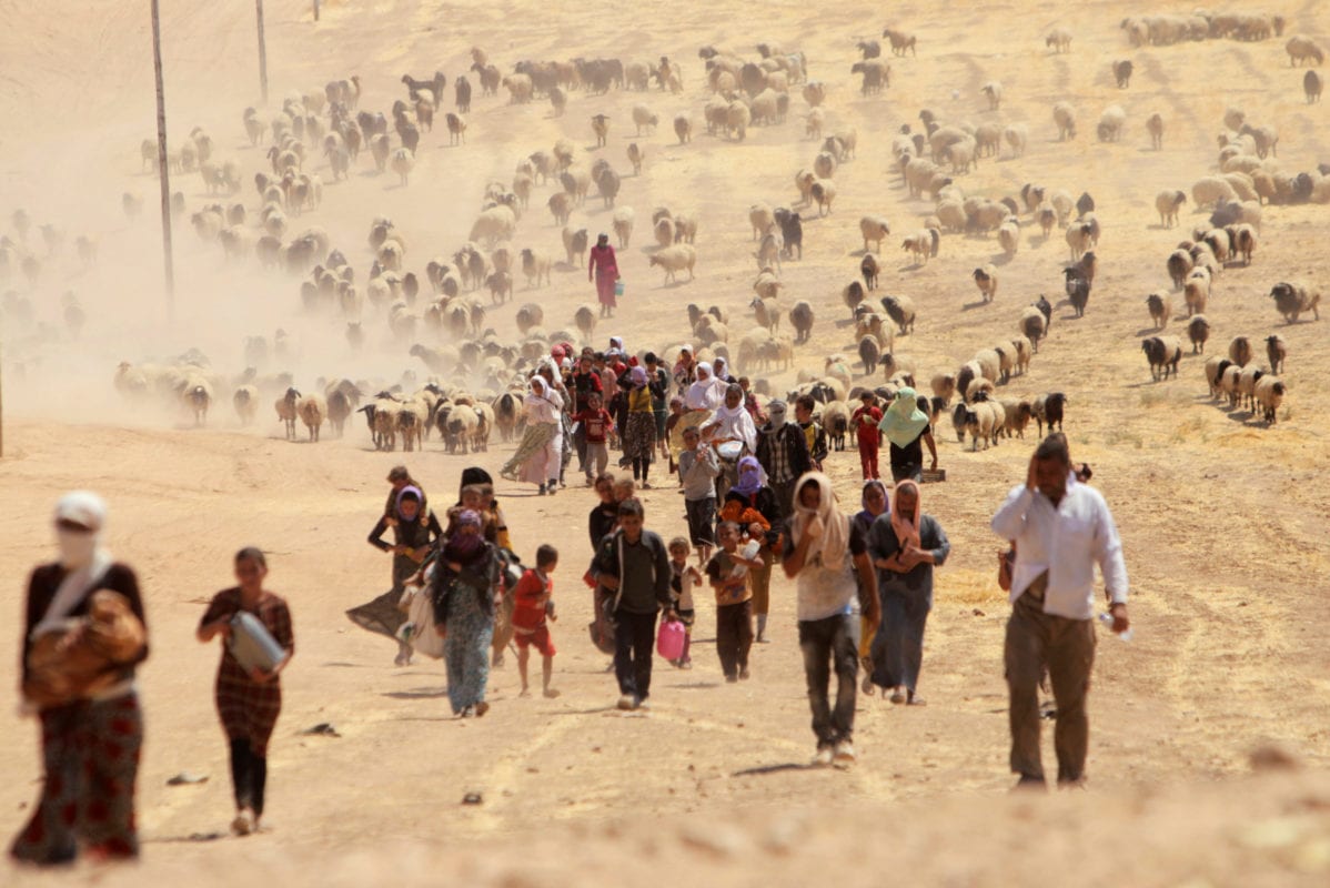 Displaced people from the minority Yazidi sect, fleeing violence from forces loyal to the Islamic State in Sinjar town, walk towards the Syrian border, on the outskirts of Sinjar mountain, near the Syrian border town of Elierbeh of Al-Hasakah Governorate August 10, 2014 [REUTERS/Rodi Said]
