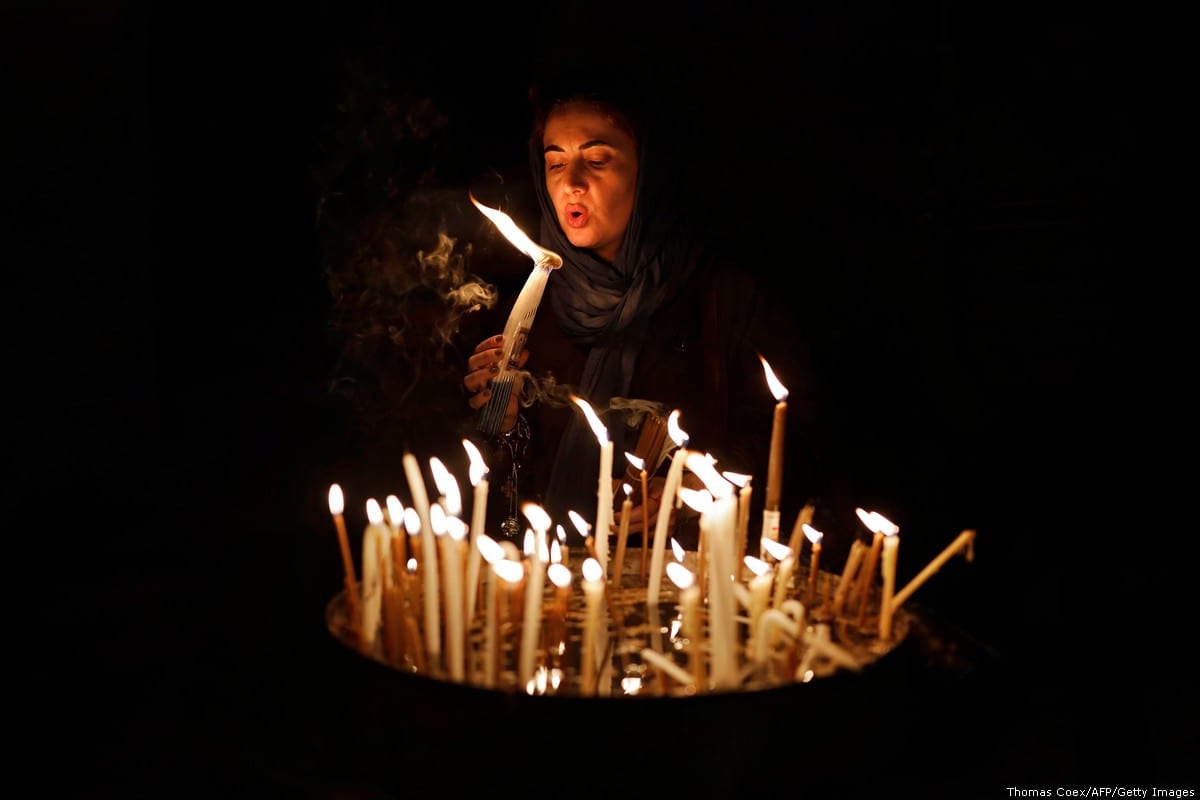 A Christian woman blows on candles inside the Church of the Holy Sepulchre in the Old City of Jerusalem, on 29 November, 2018 [Thomas Coex/AFP/Getty Images]