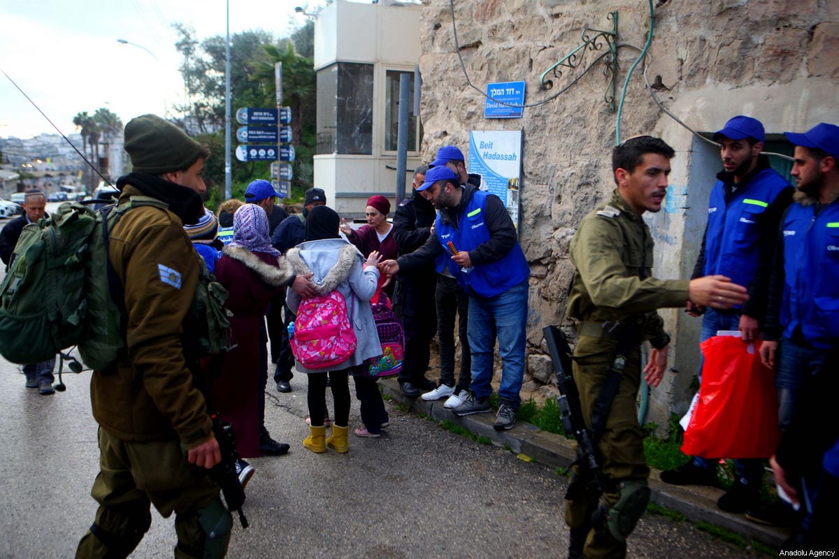 Members of the Palestinian Youth Against Settlements (YAS) activists escort children on their way to school in Hebron, West Bank on 10 February 2019 [Mamoun Wazwaz / Anadolu Agency]