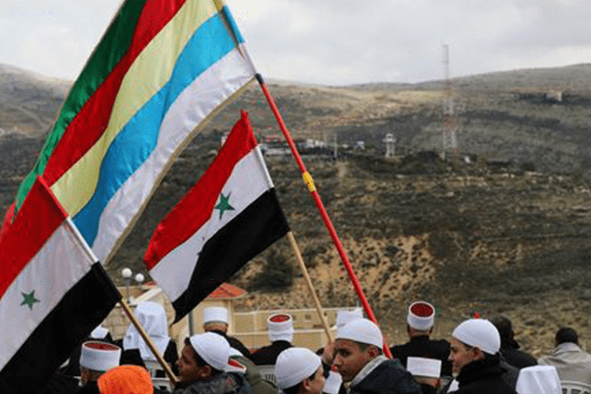 Members of the Druze community holds Syrian and Druze flags as they sit facing Syria [Twitter]