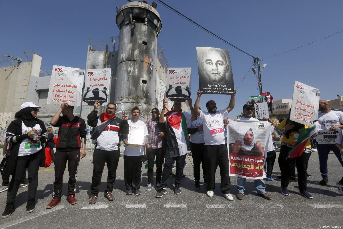 A group of people stage a demonstration in front of the Israel’s West Bank separation wall to show their support to the Palestinian prisoners in Bethlehem, West Bank on 22 March 2019 [Wisam Hashlamoun/Anadolu Agency]