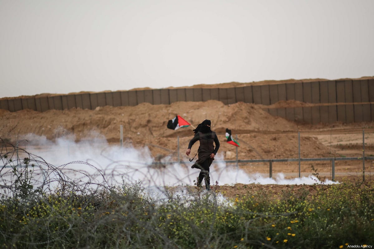 Israeli forces shoot multiple tear gas canisters at a Palestinian woman with during the anniversary march of the "Great March of Return" and "Palestinian Land Day" protests at Israel-Gaza border located near Al Bureij Refugee Camp in Gaza City, Gaza on March 30, 2019 [Hassan Jedi / Anadolu Agency]