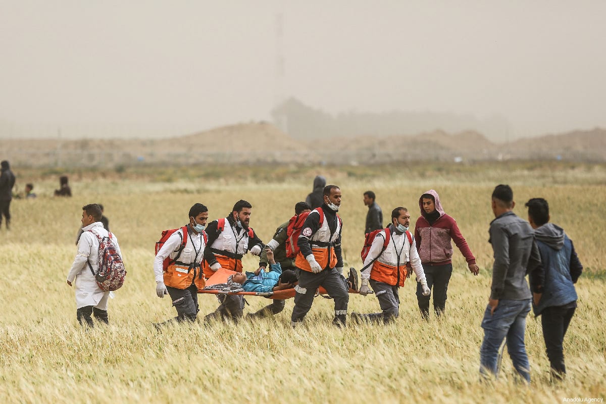 Palestinian medical staff carry away an injured Palestinian during a protest within the "Great March of Return" and "Palestinian Land Day" demonstrations at Israel-Gaza border in Khan Yunis, Gaza on 30 March 2019. [Mustafa Hassona - Anadolu Agency]