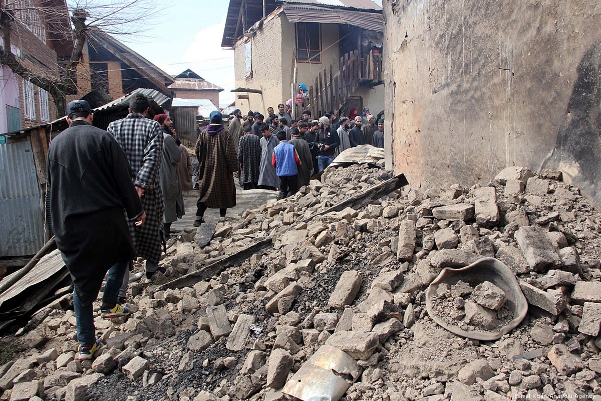 Kashmiri villagers walk past the debris of a house which was damaged by Indian forces in Kashmir on 5 March 2019 [Faisal Khan/Anadolu Agency]