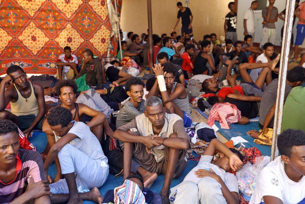 Illegal migrants sit inside the Ganzour shelter after being transferred from in the airport road due to fighting in the Libyan capital Tripoli on 5 September, 2018 [MAHMUD TURKIA/AFP/Getty Images]
