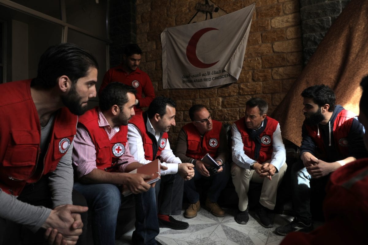 Peter Maurer (2R) President of the International Committee of the Red Cross (ICRC) talks with aid workers after arriving in the rebel-held town of Douma in Eastern Ghouta with a convoy carrying food aid on March 15, 2018. [AFP PHOTO / HAMZA AL-AJWEH / Getty]