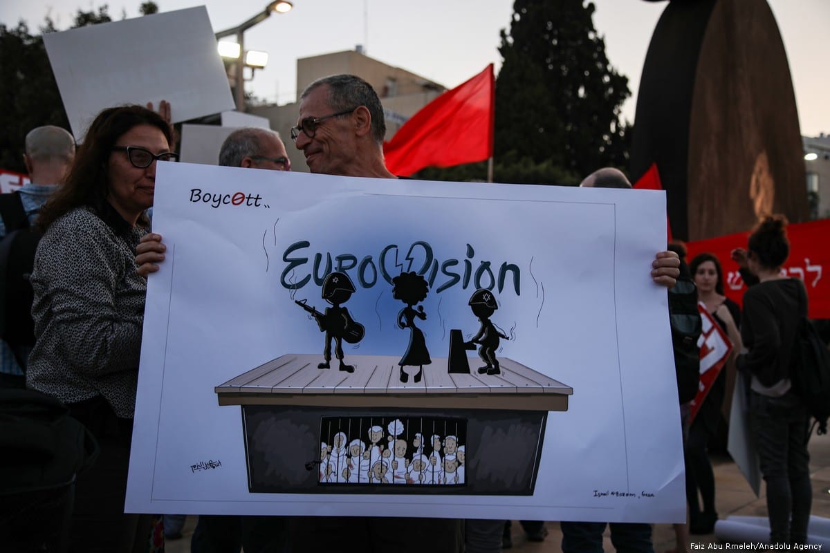 People hold placards during a protest against Eurovision Song Contest demanding the removal of continuing Israel's blockade on Gaza at Habima Square in Tel Aviv on 14 May 2019 [Faiz Abu Rmeleh/Anadolu Agency]