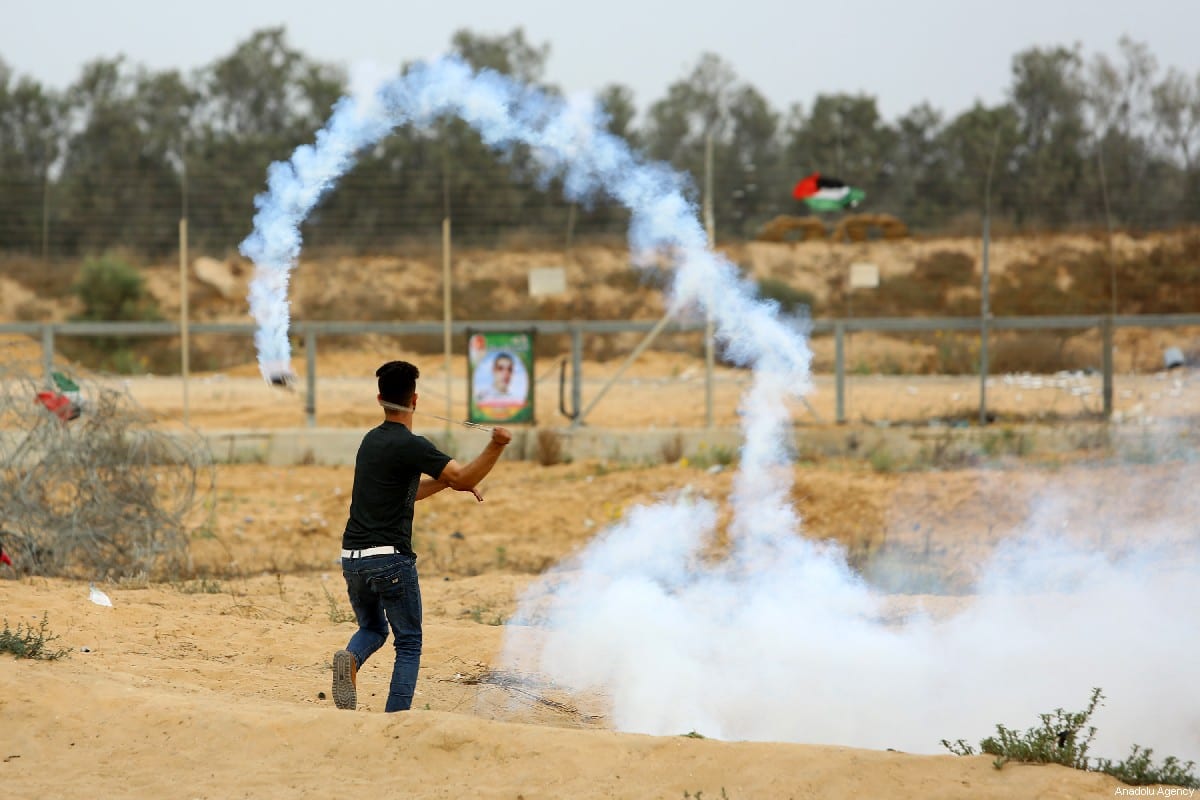 Palestinians use slingshot to throw back tear gas canister towards Israeli security forces during a protest within the "Great March of Return" near Israel-Gaza border, in eastern part of Rafah, Gaza on 31 May 2019 [Abed Rahim Khatib/Anadolu Agency]