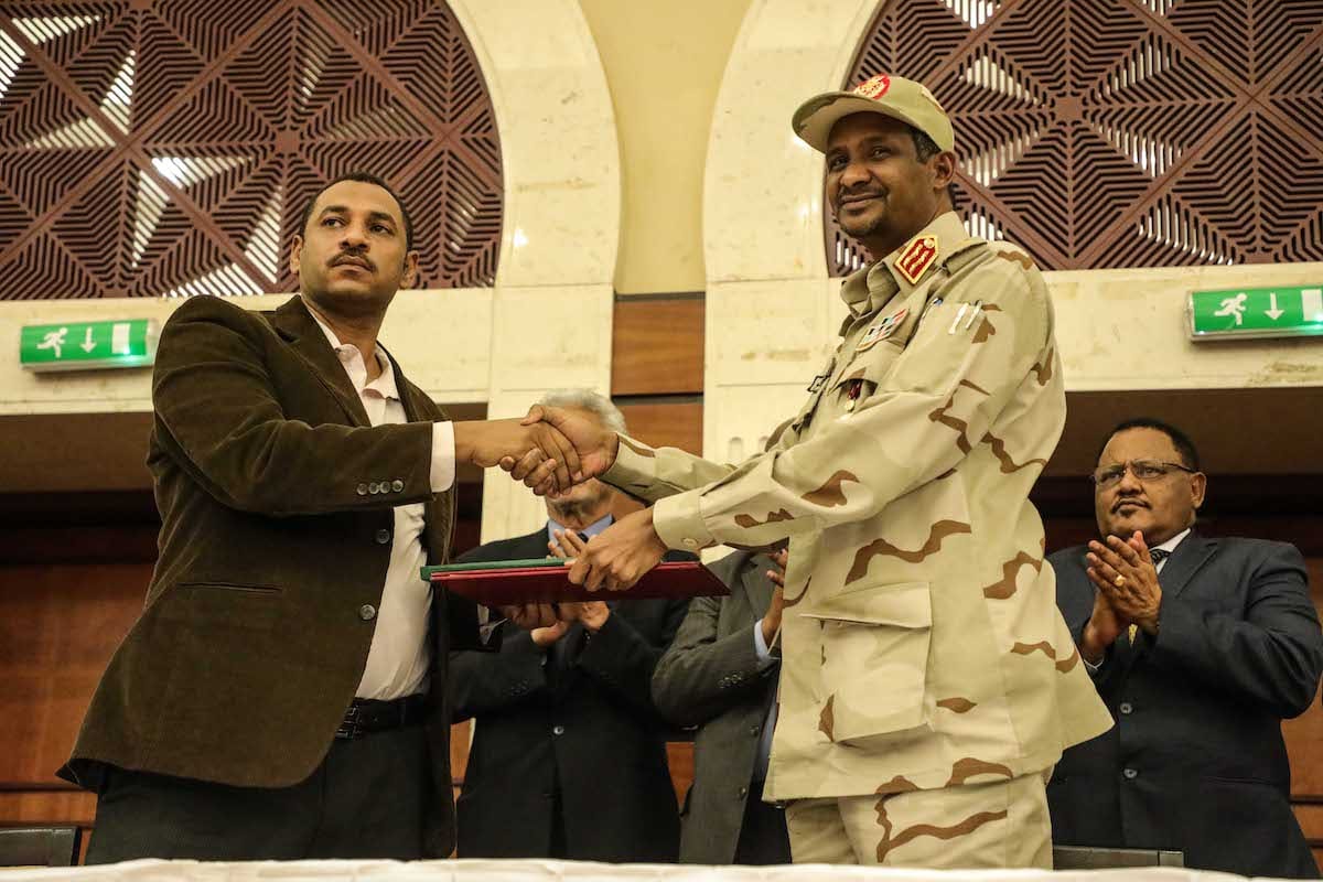Sudanese General and Vice President of Sudanese Transitional Military Council, Mohamed Hamdan Dagalo (R) and Sudan's Forces of Freedom and Change coalition's leader Ahmad al-Rabiah (L) shake hands after signing an agreement in Khartoum on 17 July 2019. [Mahmoud Hjaj - Anadolu Agency]