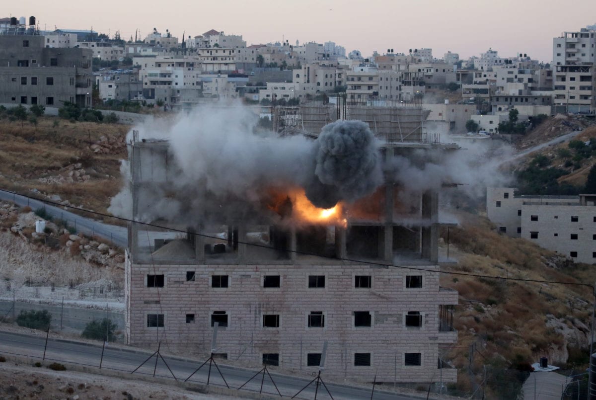Smoke rises as Israeli forces begin to raze a building on the grounds that the building was close to the wire barriers, which is continuation of the separation wall, in the neighborhood of Wadi Homs in East Jerusalem on 22 July 2019. [Issam Rimawi - Anadolu Agency]