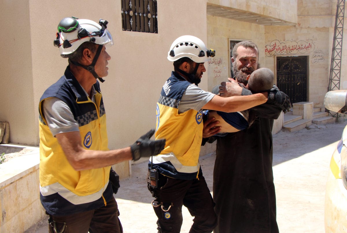 A dead body of a boy is being carried away by white helmet members a after Assad Regime's warplanes carried out airstrike over Kansafra town of Idlib de-escalation zone in Syria on 4 July 2019. [Syrian Civil Defense/ White Helmets / Handout - Anadolu Agency]
