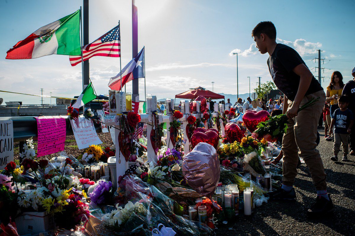 A mourner places flowers on the ground during a vigil outside a Walmart ore following a mass shooting in El Paso, Texas on 6 August 2019 [Luke E. Montavon/Bloomberg via Getty Images]