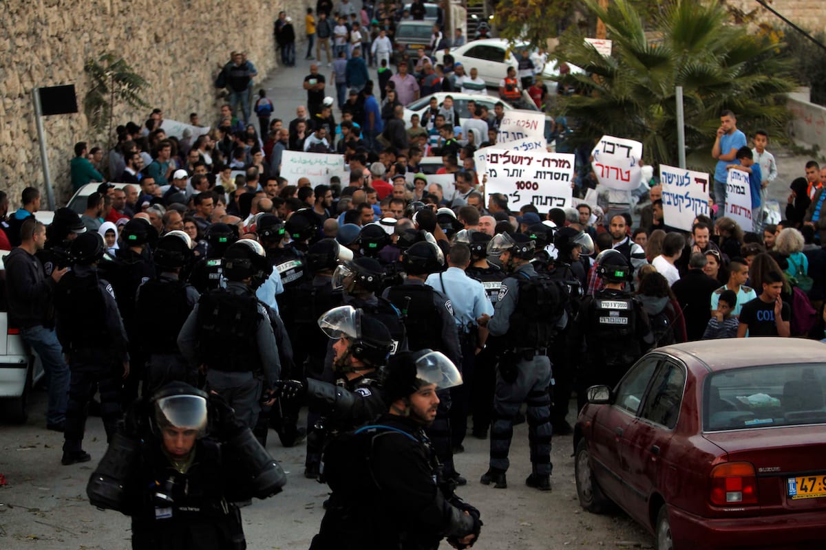 Palestinian protesters hold placards in front of Israeli border police, during a demonstration at the east Jerusalem Arab neighborhood of Issawiya, 12 November 2014. [Muammar Awad-Apaimages]