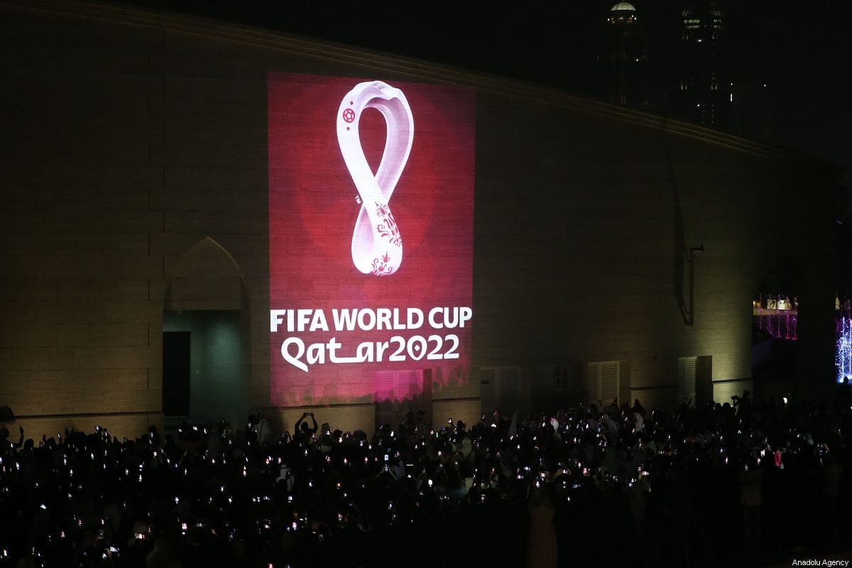 Hundreds of people take a photo as the official logo of the 'FIFA World Cup Qatar 2022' is reflected on a wall in Doha, Qatar on 3 September 2019 [Mohammed Dabbous/Anadolu Agency]