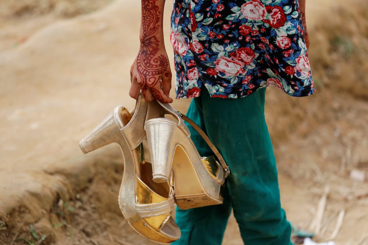 A Bangladeshi girl carries her sister's shoes near Cox's Bazar, Bangladesh on 8 December 2017. [REUTERS/Damir Sagolj]