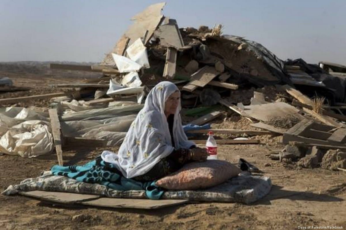 A Palestinian woman sits in front of her demolished home after Israeli forces ordered it for it be destroyed in the Negev on 15 February 2015 [Days of Palestine/Facebook]