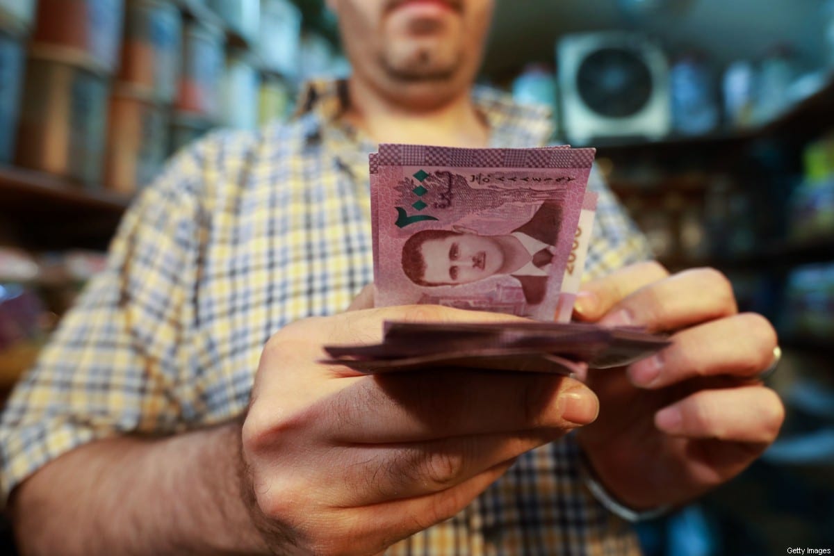 A merchant counts Syrian pound notes, bearing a portrait of the Syrian President Bashar al-Assad, at the Bzourieh market in the centre of the Syrian capital Damascus. [LOUAI BESHARA/AFP via Getty Images]