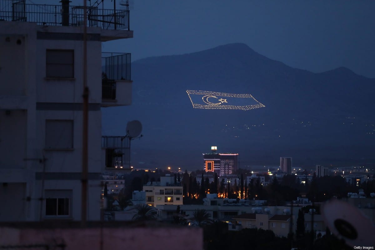 A massive flag of the self-proclaimed Turkish Republic of North Cyprus (TRNC) lies illuminated on a mountainside on the Turkish, northern part of the island as viewed from a residential area in the southern, Greek part of Nicosia on March 7, 2017 in Nicosia, Cyprus. [Sean Gallup/Getty Images]