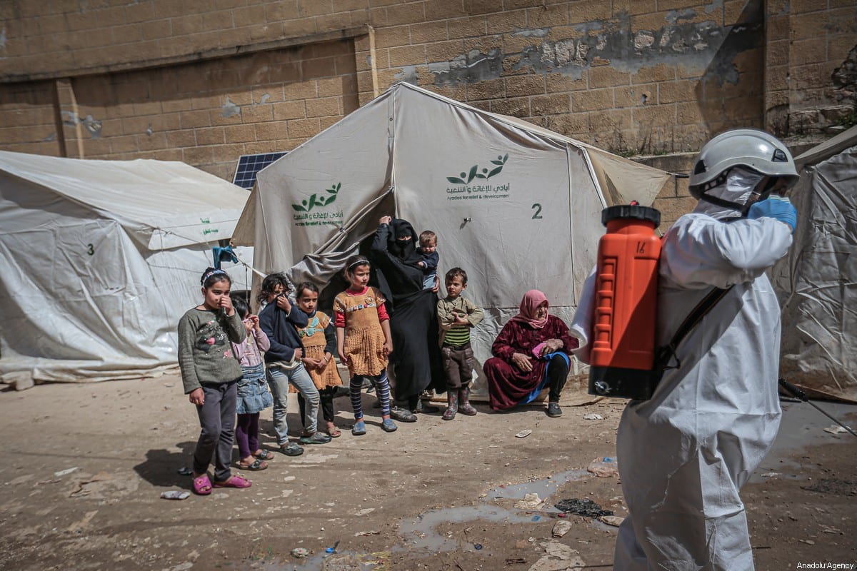Members of the Syrian Civil Defence (White Helmets) disinfect buildings and tents where families live collectively as a preventive measure against coronavirus (Covid-19) pandemic in Idlib, Syria on 24 March 2020. [Muhammed Said - Anadolu Agency]