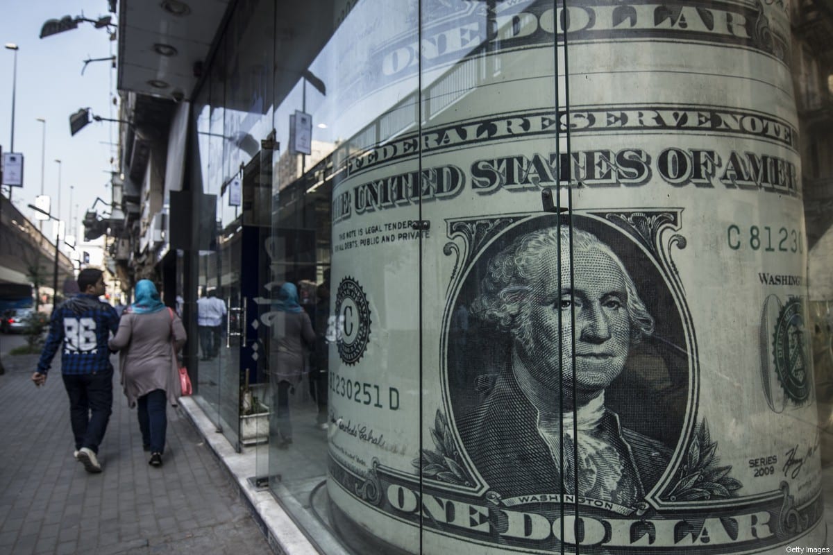 People walk past a currency exchange shop displaying a giant US dollars banknote in downtown Cairo on November 3, 2016. [KHALED DESOUKI/AFP via Getty Images]