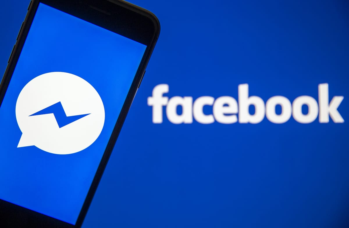 A mobile phone screen displays the Facebook Messenger logo in front of a computer screen showing the Facebook sign on 27 February, 2020 [Ali Balıkçı/Anadolu Agency]