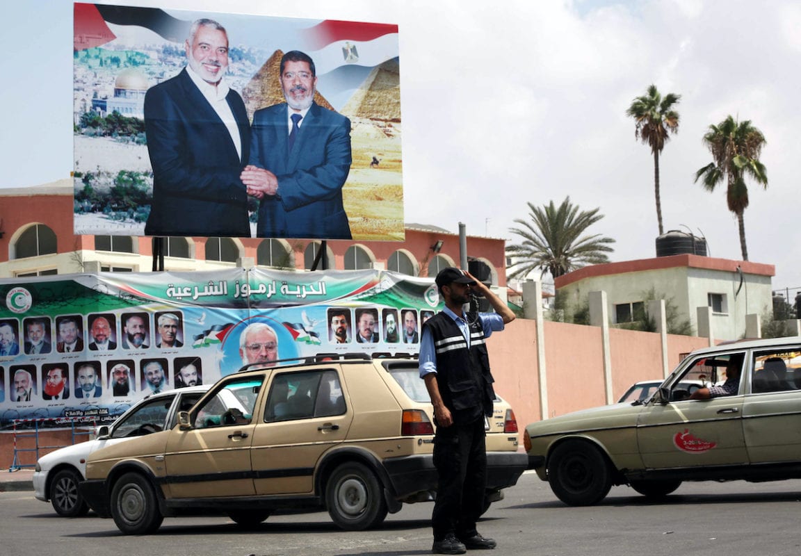 A Palestinian Hamas policeman organizes the traffic in front of a photograph released by Hamas, Egyptian President Mohammed Morsi, right, meets the Palestinian Prime Minister in Gaza, Ismail Haniyeh, in Gaza city on 29 August 2012. [Ashraf Amra/Apaimages]