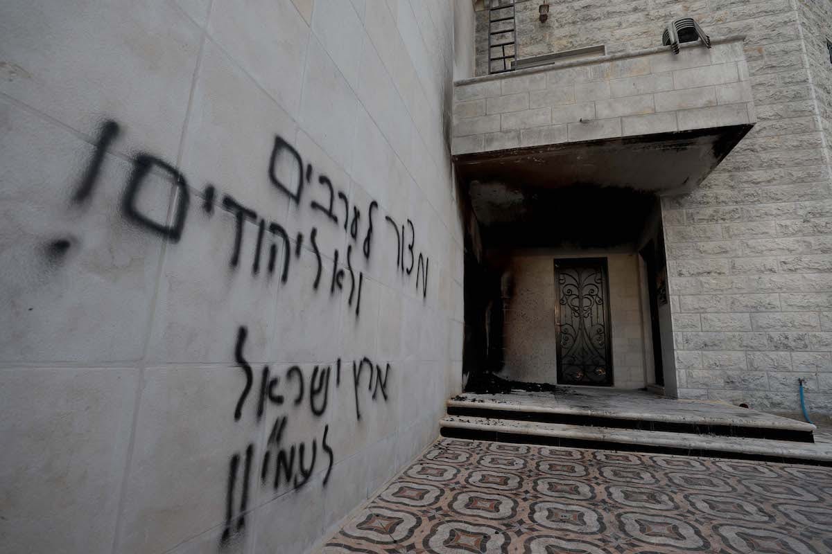 A view from the Al-Bir Wal-Ihsan Mosque damaged by Jewish settlers and a wall with racist slogans are seen in Al-Bireh district of Ramallah, West Bank on July 27, 2020. [İssam Rimawi - Anadolu Agency]