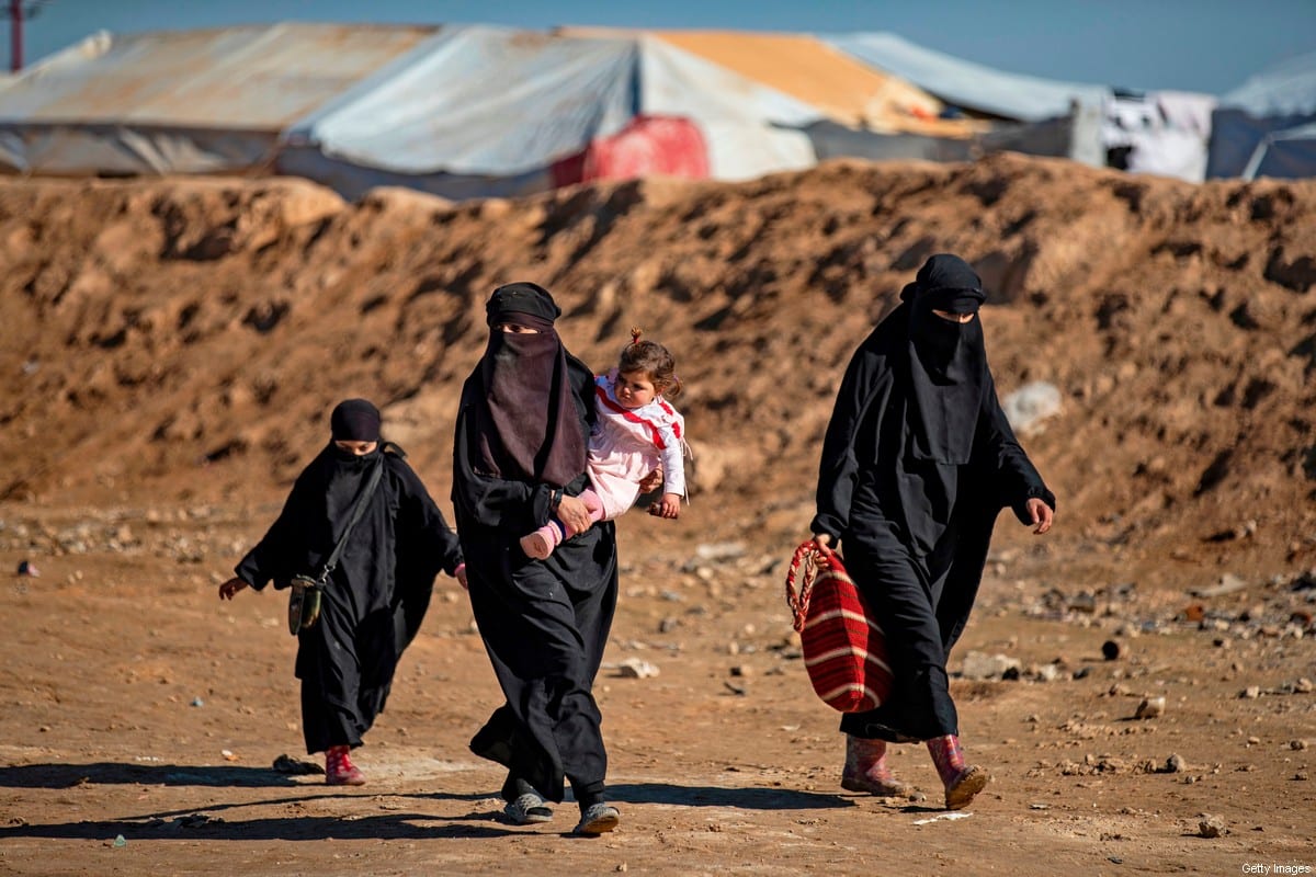 Women and accompanying children walk by at the Kurdish-run al-Hol camp for the displaced in the al-Hasakeh governorate in northeastern Syria on 14 January 2020, where families of Daesh foreign fighters are held. [DELIL SOULEIMAN/AFP via Getty Images]