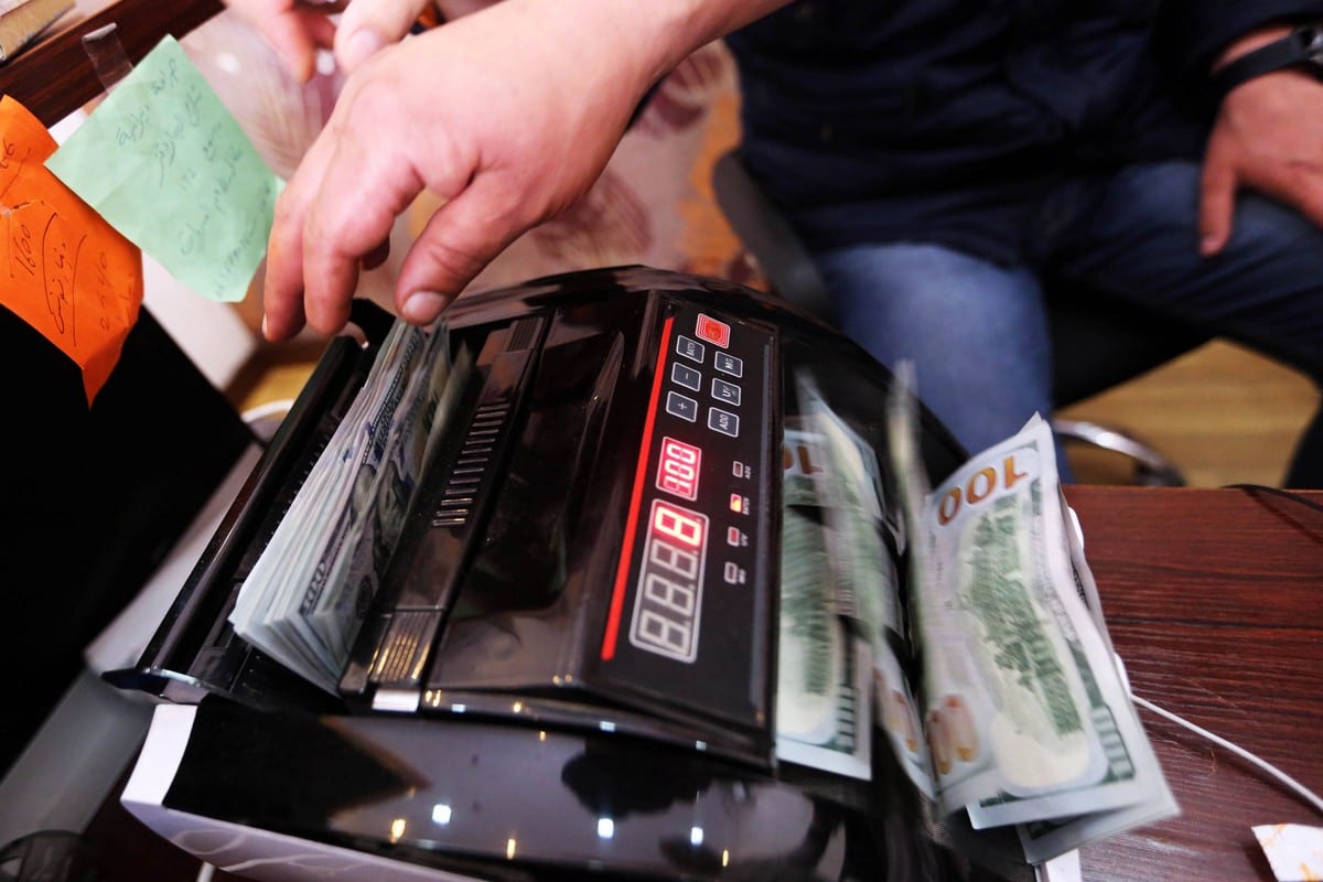 An employee counts US dollars at a currency exchange in the Libyan capital Tripoli, on 4 April 2016 [MAHMUD TURKIA/AFP/Getty Images]