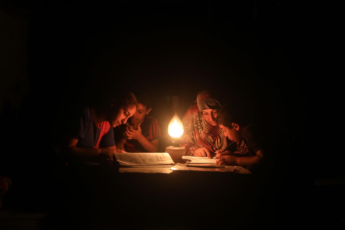 A Palestinian boy poses behind candles during a power outage