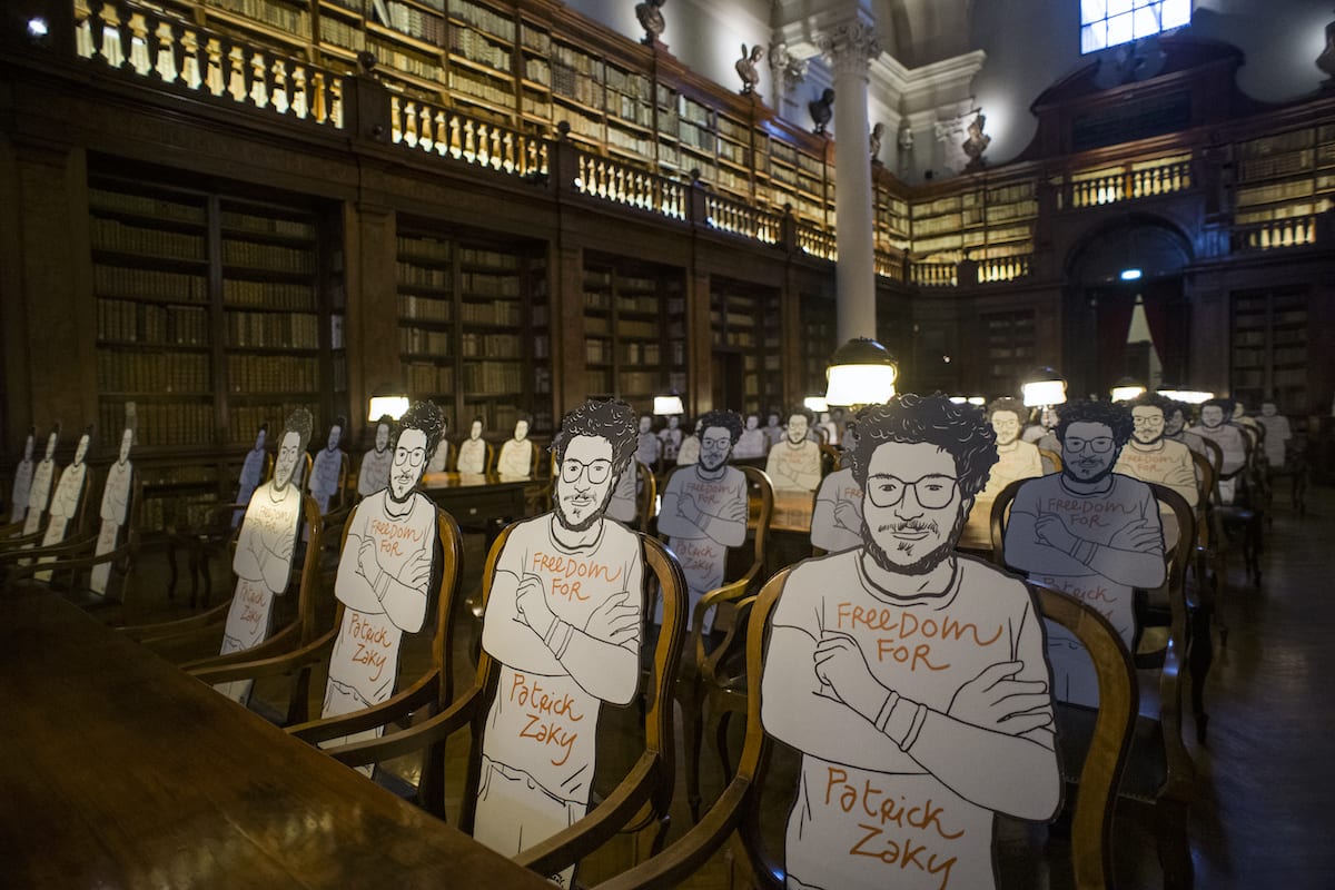 Silhouette cut-outs of Patrick Zaki, a EIPR researcher who was arrested by Egyptian forces, is seen at the Aula Magna of the University Library of Bologna on 16 July 2020 in Bologna, Italy [Michele Lapini/Getty Images]