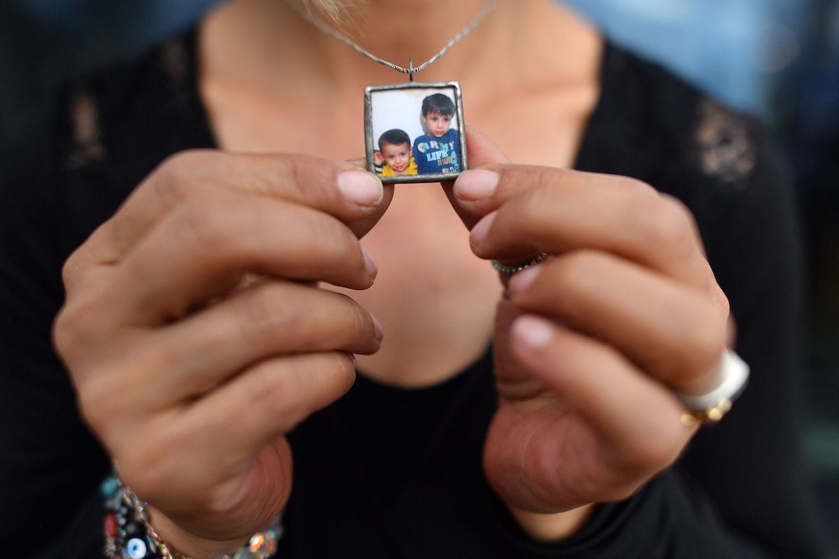 Tima Kurdi, co-founder of the The Kurdi Foundation, holds her necklace bearing an image of her nephews, Alan and Ghalib Kurdi, as she poses for a photograph in London on 15 August 2018. [BEN STANSALL/AFP via Getty Images]
