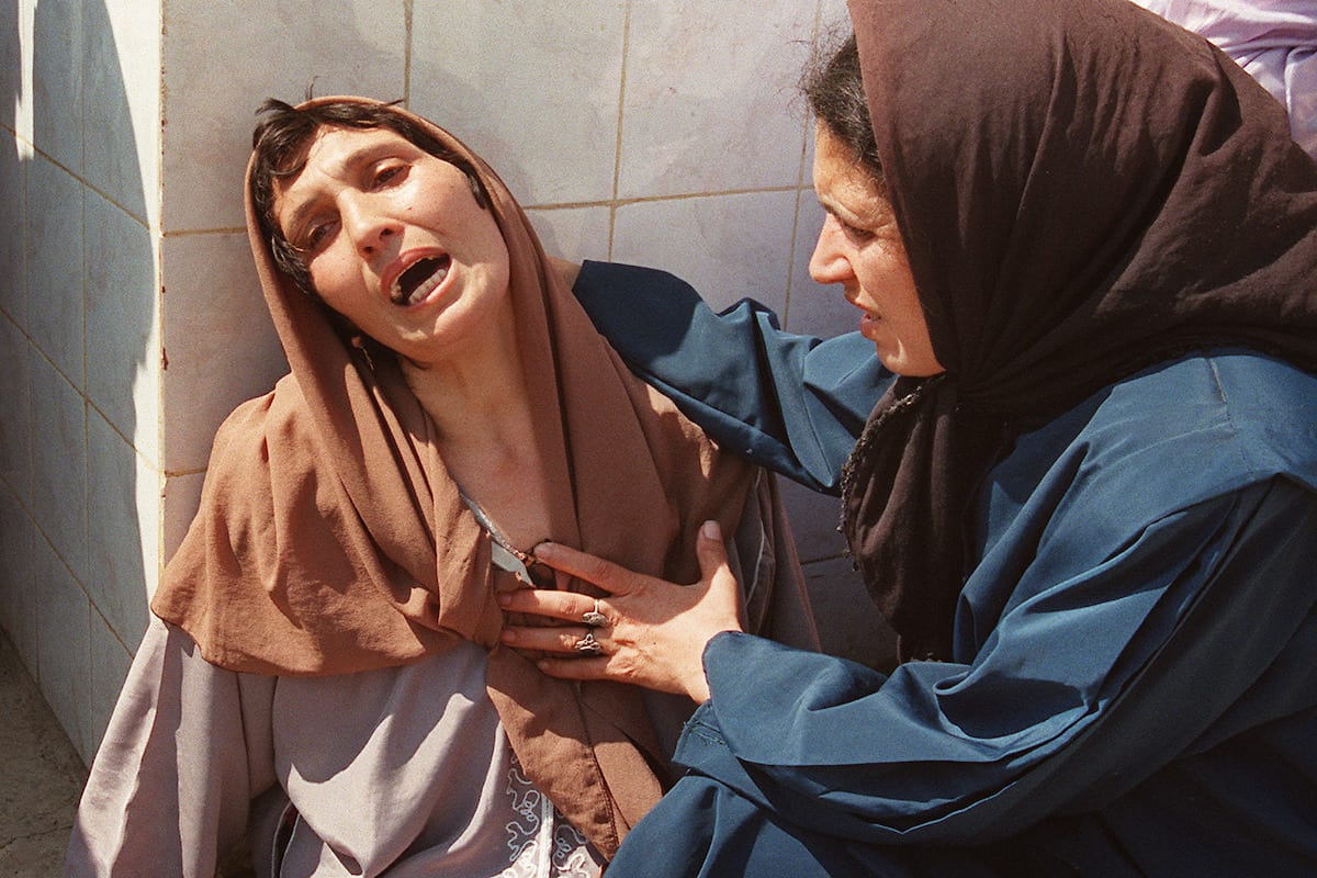 A distraught woman, who later was called the 'Madonna of Bentalha' is comforted by a relative at Zmirli hospital after having lost all her family on 23 September 1997 [HOCINE ZAOURAR/AFP via Getty Images]