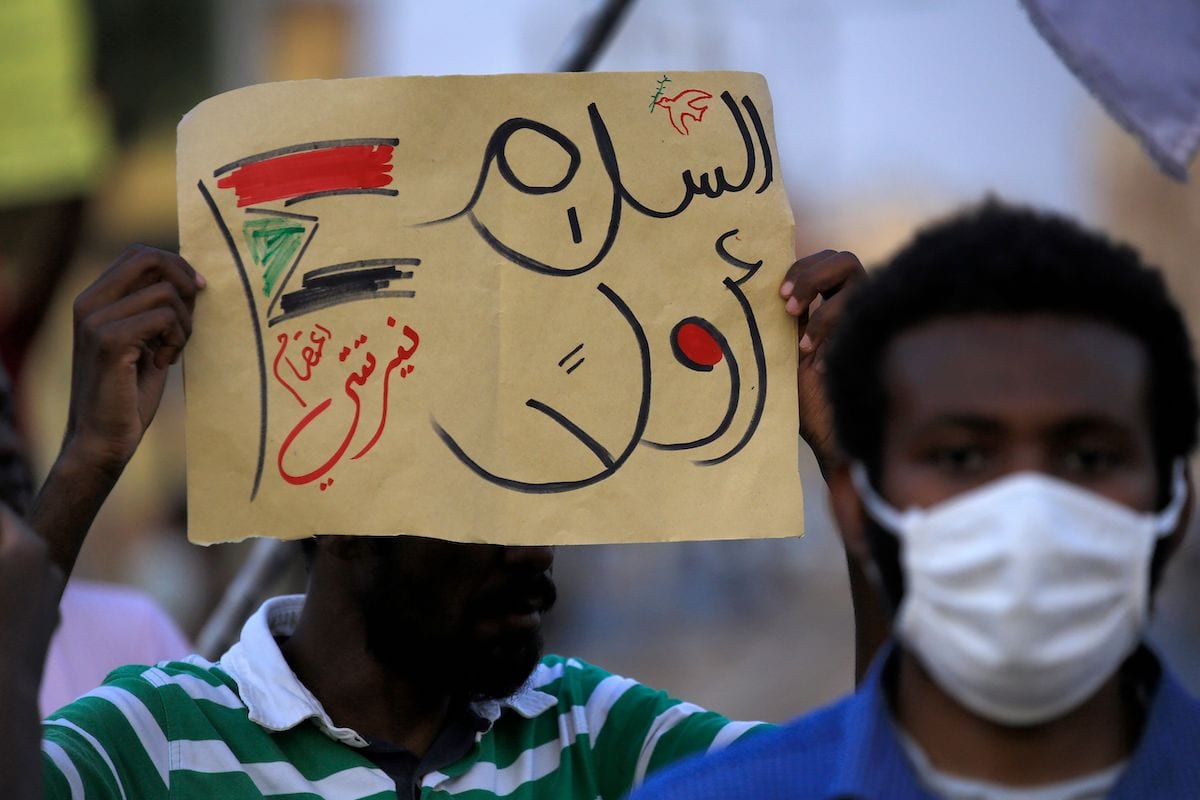 A demonstrator holds up a sign reading in Arabic "peace first, Nertiti sit-in" along with a drawn Sudanese flag, during a protest outside the Sudanese Professionals Association in the Garden City district of Sudan's capital Khartoum on 4 July 2020, in solidarity with the people of the Nertiti region of Central Darfur province in the country's southwest. [ASHRAF SHAZLY/AFP via Getty Images]